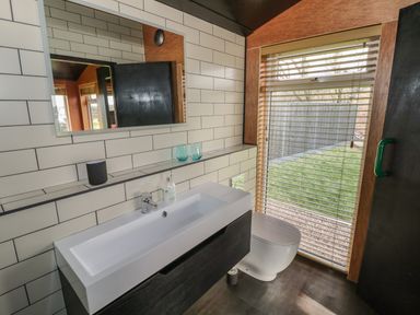 A bathroom with a sink cabinet mirror toilet and window blinds at The Tractor Shed in Lower Broadheath Worcester