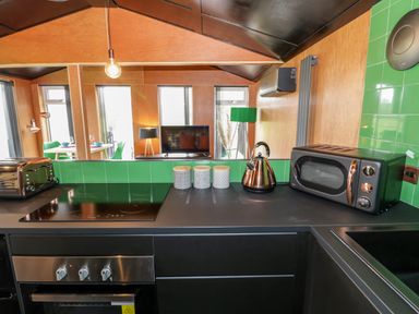 A kitchen countertop with a stove toaster kettle microwave and containers at The Tractor Shed in Lower Broadheath Worcester