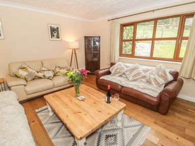 A living room with two sofas a wooden coffee table with flowers and wine in Bryn Elsi in Betws-Y-Coed