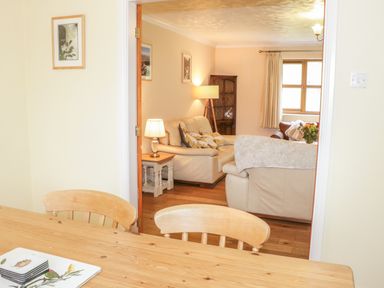 A dining table with chairs and a living room with sofas and lamps at Bryn Elsi in Betws-Y-Coed