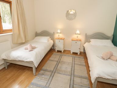 A bedroom with two single beds white bedding bedside tables lamps and a window at Bryn Elsi in Betws-Y-Coed