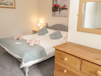 A bedroom with a double bed with pillows and towels a wooden dresser and a mirror at Bryn Elsi in Betws-Y-Coed