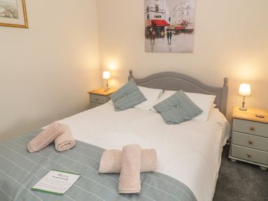 A bedroom with a double bed two bedside tables with lamps and towels on the bed at Bryn Elsi in Betws-Y-Coed