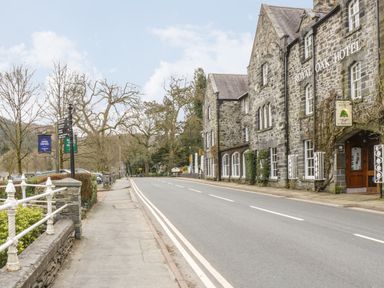 A stone building labeled Royal Oak Hotel next to a street with a sidewalk and leafless trees at Bryn Elsi in Betws-Y-Coed