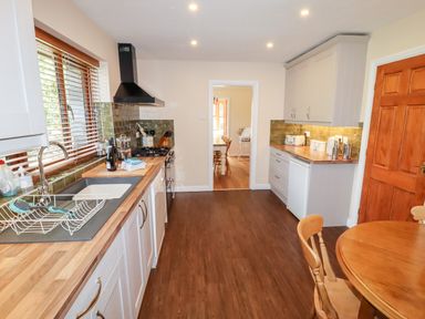 A kitchen with wooden countertops white cabinets wooden floor and a round wooden dining table at Bryn Elsi in Betws-Y-Coed
