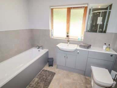 A bathroom with a bathtub a sink under a window and a toilet at Bryn Elsi in Betws Y Coed