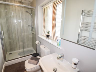 A bathroom with a glass shower enclosure a toilet a sink and a window with blinds at Bryn Elsi in Betws-Y-Coed