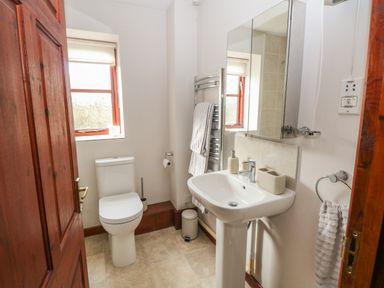 A bathroom with a toilet sink mirror and towel racks at Seaview Cottage in Salthouse Norfolk