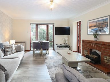 A living room with sofas a coffee table a dining table with chairs a wall-mounted television and a fireplace at Seaview Cottage in Salthouse Norfolk