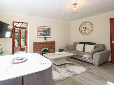 A living room with a gray sofa a marble coffee table a brick fireplace and wall clock at Seaview Cottage in Salthouse Norfolk