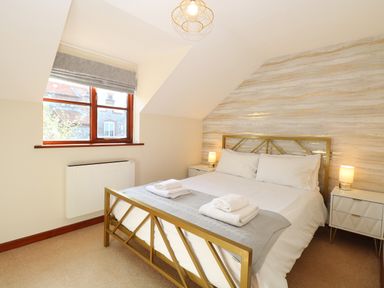 A bedroom with a double bed two bedside tables lamps and a window at Seaview Cottage in Salthouse Norfolk