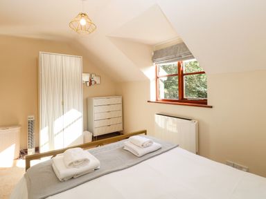 A bedroom with a bed and folded towels on top a wardrobe a chest of drawers and a window with a blind at Seaview Cottage in Salthouse Norfolk