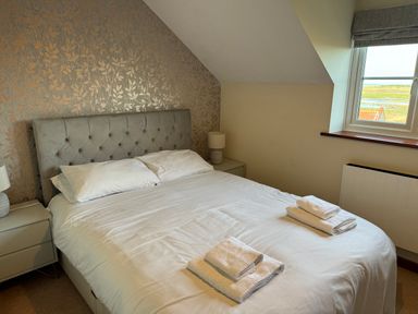 A bedroom with a double bed and folded towels on the bed at Seaview Cottage in Salthouse Norfolk