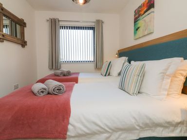 A bedroom with two single beds with red throws and rolled towels at Seaquel in Westward Ho