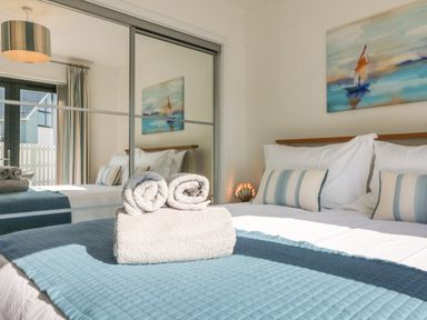 A bedroom with a bed towels pillows and a painting above the headboard at Seaquel in Westward Ho