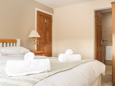 A bedroom with a bed with rolled white towels and a bedside table with a lamp at Maple in Falmouth