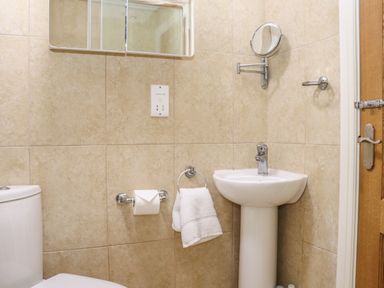 A bathroom with a toilet sink towel rack and mirror at Maple in Falmouth