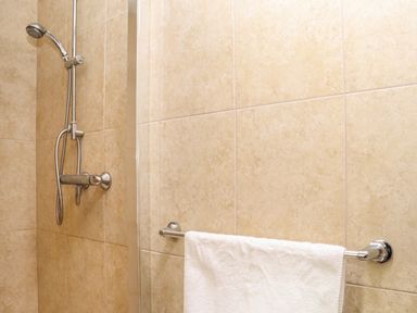 A shower with a handheld showerhead and a white towel on a rack on tiled walls at Maple in Falmouth