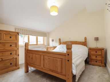 A bedroom with a wooden bed and matching furniture under a window at Maple in Falmouth