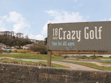 Outdoor mini golf course with a sign reading 18 hole Crazy Golf fun for all ages at Maple in Falmouth