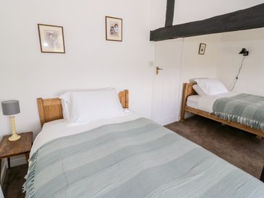 A bedroom with two single beds with wooden headboards and green blankets at Manor Farm Cottage in Hill Croome near Upton Upon Severn