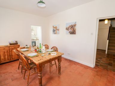A dining room with a wooden table and chairs set for a meal a wooden sideboard and two animal paintings on the wall at Manor Farm Cottage in Hill Croome near Upton Upon Severn