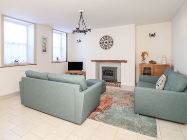 A living room with two teal sofas a colorful rug a fireplace and a television at Bliss On The Bay in Weymouth
