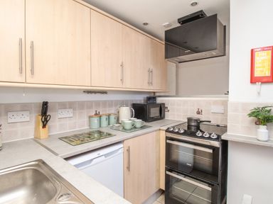 A kitchen with countertops cabinets a sink a stove microwave kettle and canisters at Bliss On The Bay Weymouth