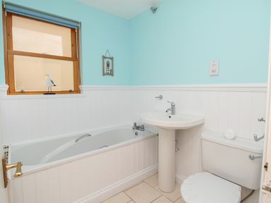 A bathroom with a bathtub sink toilet and window at Bliss On The Bay in Weymouth