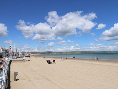 A sandy beach with people and water at Bliss On The Bay in Weymouth