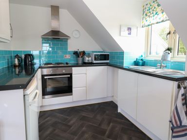 A kitchen with white cabinets black countertops turquoise tiled backsplash and stainless steel appliances at Spinney's Den in Knapton