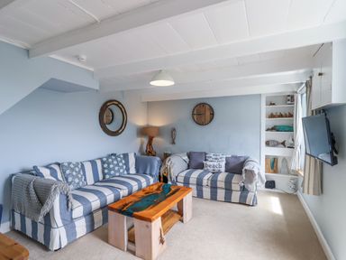 A living room with a sofa, coffee table, and television at 2 Cliff Cottages West Portholland near Gorran Haven