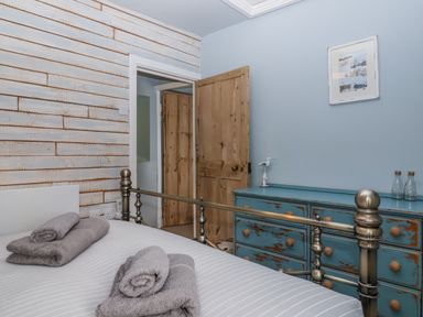 A bedroom with a bed and towels folded at 2 Cliff Cottages near West Portholland