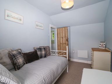 A bedroom with a bed and a wooden door at 2 Cliff Cottages near West Portholland