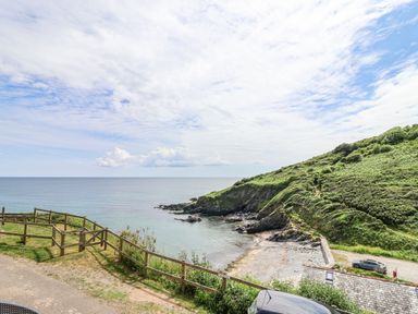 A view of the sea with surrounding grass and rocks at 2 Cliff Cottages West Portholland near Gorran Haven