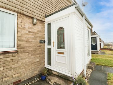 A front door entrance of a house with a pathway and grass at Sea Snug in Spittal