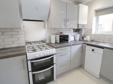 A kitchen with a gas stove oven microwave kettle and dishwasher at 22 Gwel Yr Wyddfa in Menai Bridge