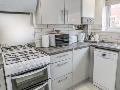 A kitchen with a gas stove microwave paper towel kettle toaster and dishwasher at 22 Gwel Yr Wyddfa in Menai Bridge