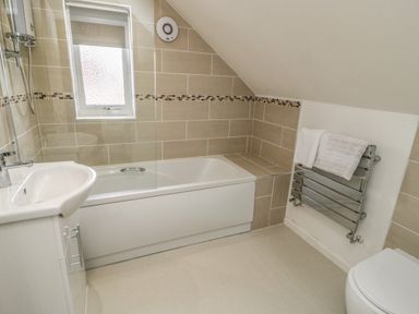 A bathroom with a bathtub shower sink and heated towel rack at 22 Gwel Yr Wyddfa in Menai Bridge