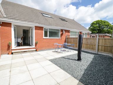 A patio area with a table and chairs outside a brick house at 22 Gwel Yr Wyddfa in Menai Bridge