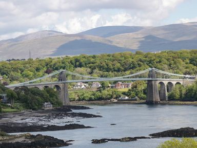 A suspension bridge crossing a river with houses and trees in the background at 22 Gwel Yr Wyddfa in Menai Bridge