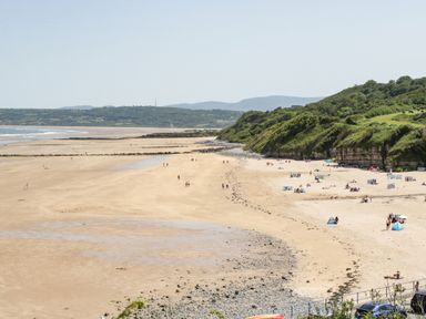 A beach with people, sand, and rocky cliffs at 22 Gwel Yr Wyddfa in Menai Bridge