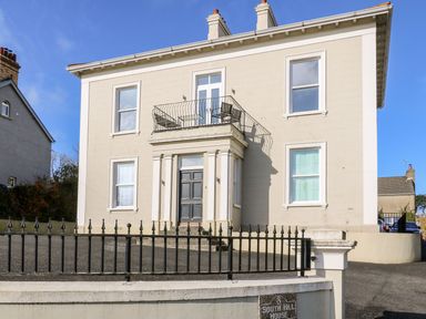 A beige two-story house with black door and balcony above the entrance at Sea Breeze in Ballycastle