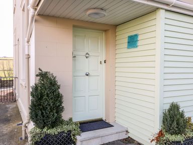 A house entrance with a pale green door and potted plants on either side at Sea Breeze in Ballycastle