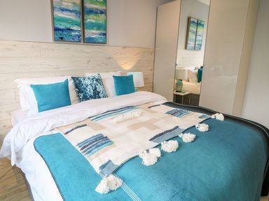 A bedroom with a bed with blue and white bedding and three blue cushions at Sea Breeze in Ballycastle
