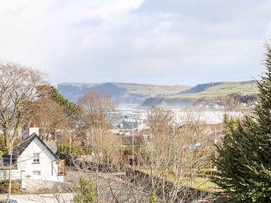 A coastal village with houses and trees overlooking cliffs and the sea at Sea Breeze in Ballycastle