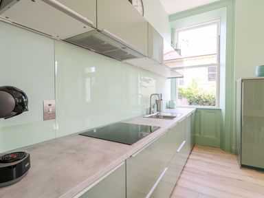 A kitchen with a countertop stove a sink and a window at Beachcomber in Ballycastle