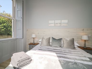 A bedroom with a bed three pillows and two bedside tables with lamps at Beachcomber in Ballycastle