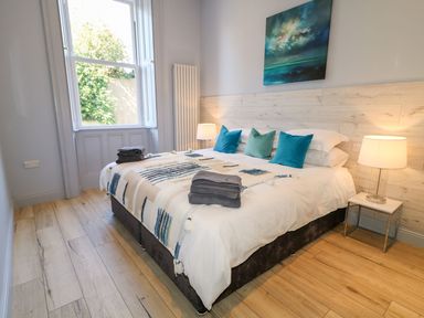 A bedroom with a bed with pillows and folded towels next to a window and two bedside lamps at Beachcomber in Ballycastle
