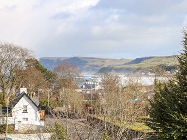 A view of a coastal landscape with houses, trees, and hills in the distance at Beachcomber in Ballycastle